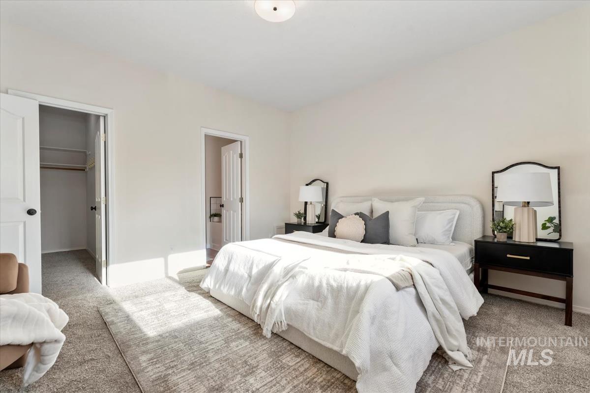 Bedroom featuring carpet floors, a walk in closet, and ensuite bathroom