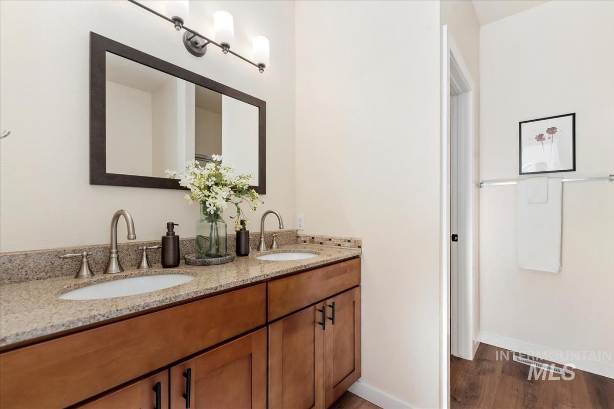 Full bathroom featuring double vanity and dark wood finished floors