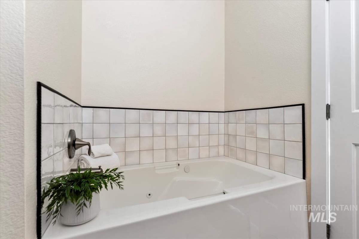 Full bathroom with a whirlpool tub and a textured wall