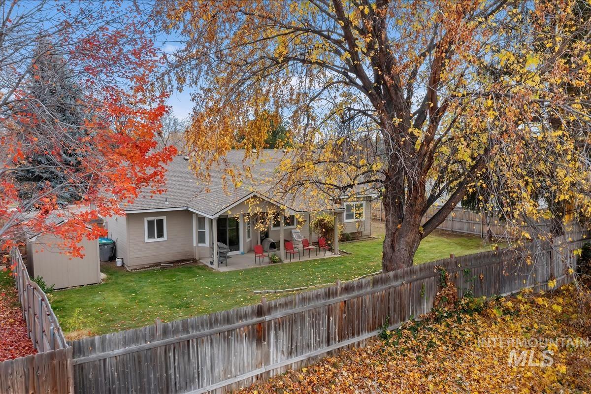 Back of house featuring a patio, a fenced backyard, a storage shed, and roof with shingles