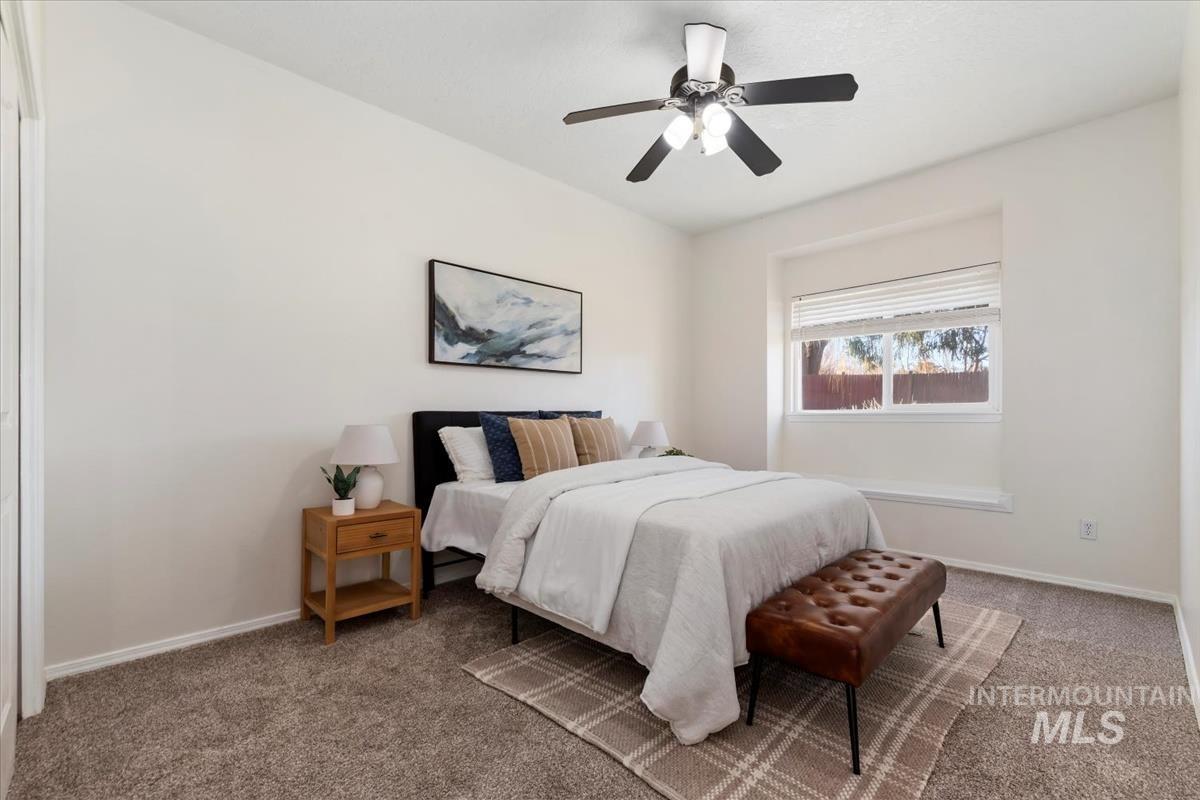 Carpeted bedroom featuring a ceiling fan and baseboards