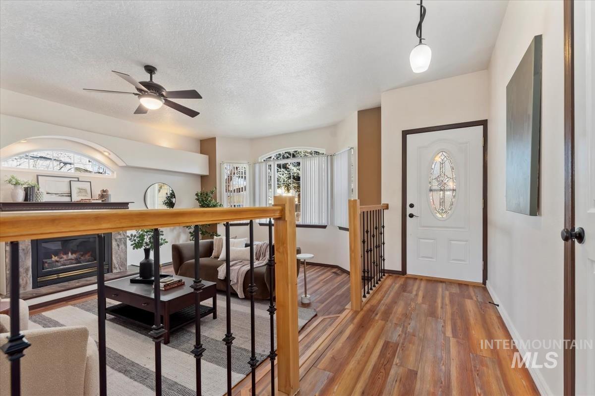 Foyer entrance featuring wood-type flooring, a glass covered fireplace, a ceiling fan, and a textured ceiling