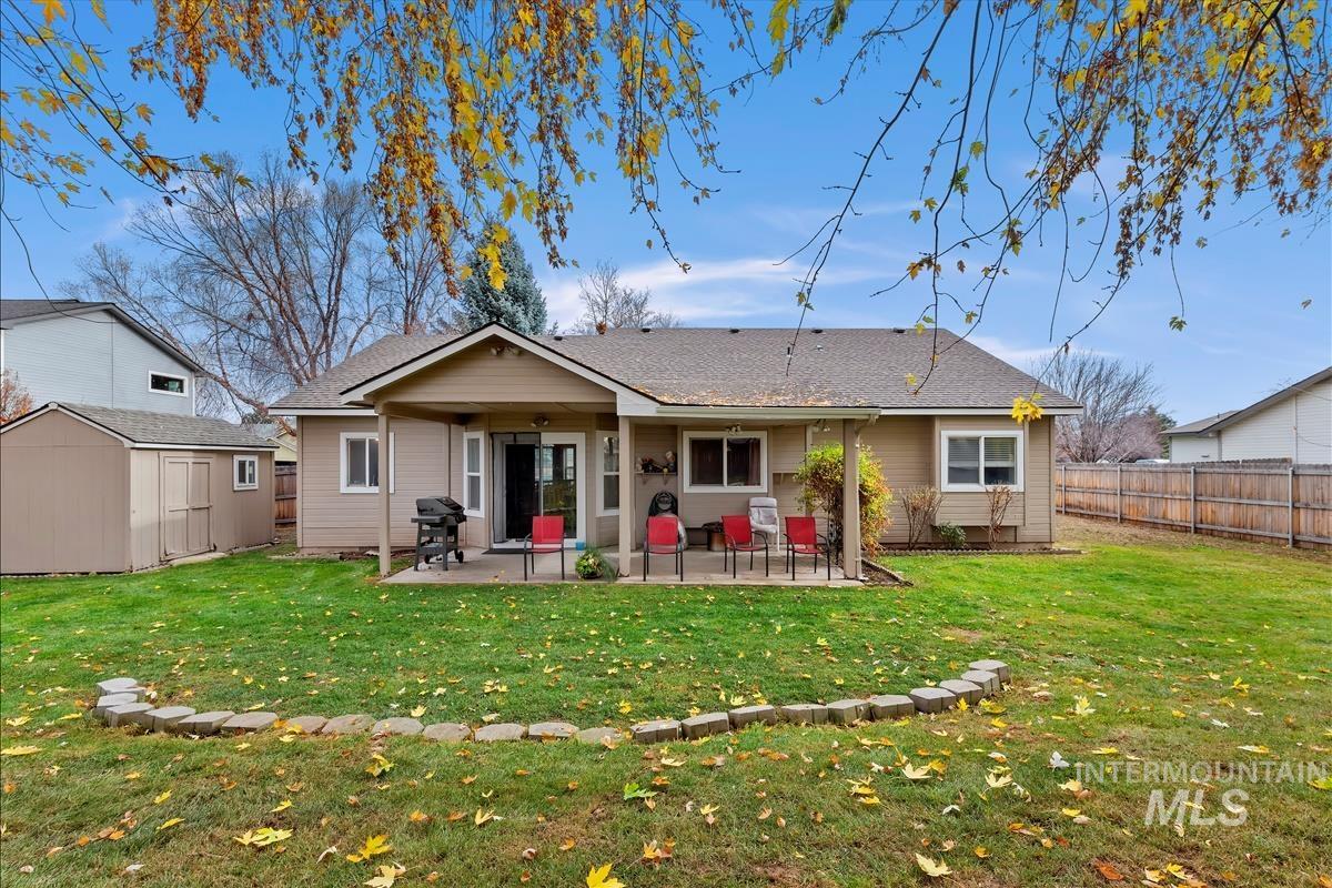 Back of house with a shingled roof, a patio area, a storage shed, and a fenced backyard