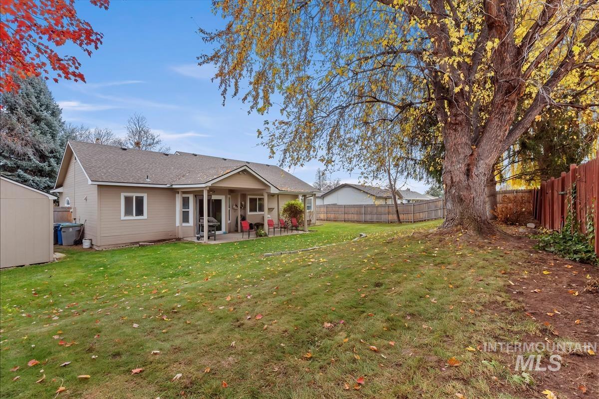 Rear view of house with a patio, a fenced backyard, a storage unit, and roof with shingles