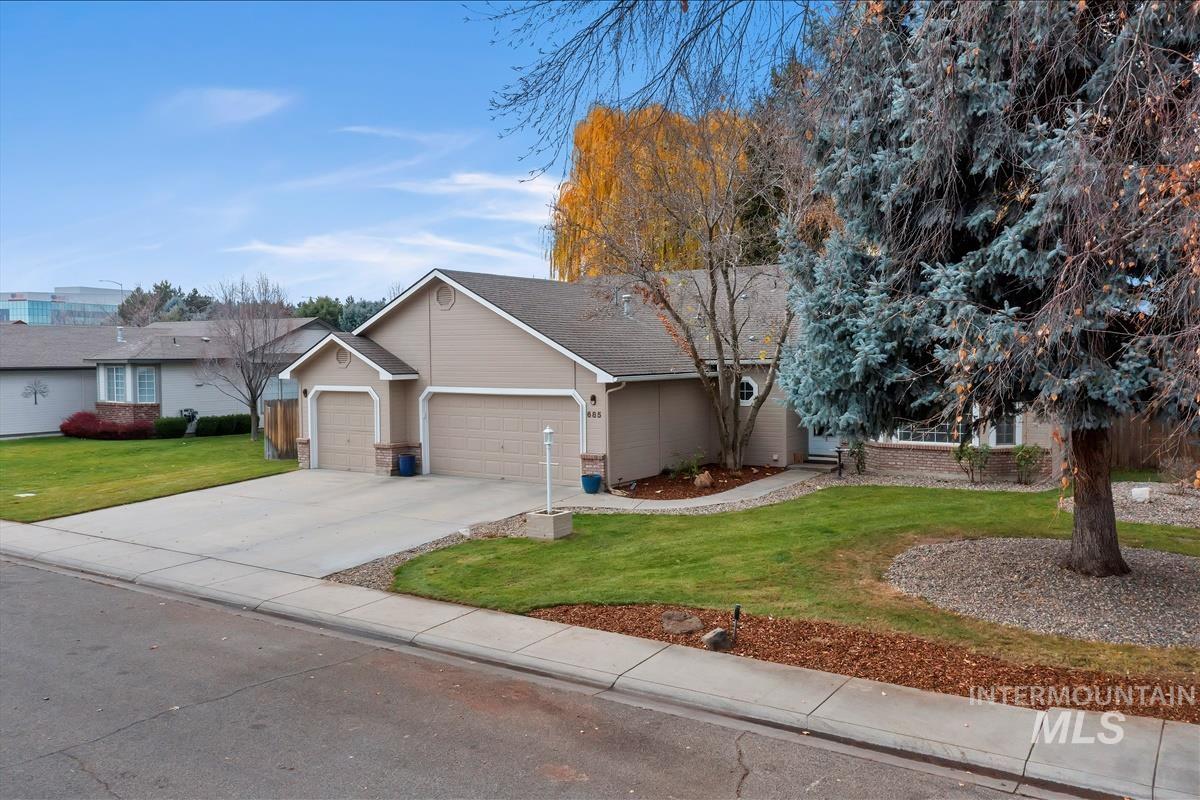 View of front of house with brick siding, an attached garage, a front lawn, and driveway