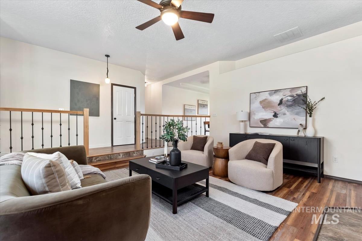 Living area featuring a textured ceiling, wood finished floors, and ceiling fan