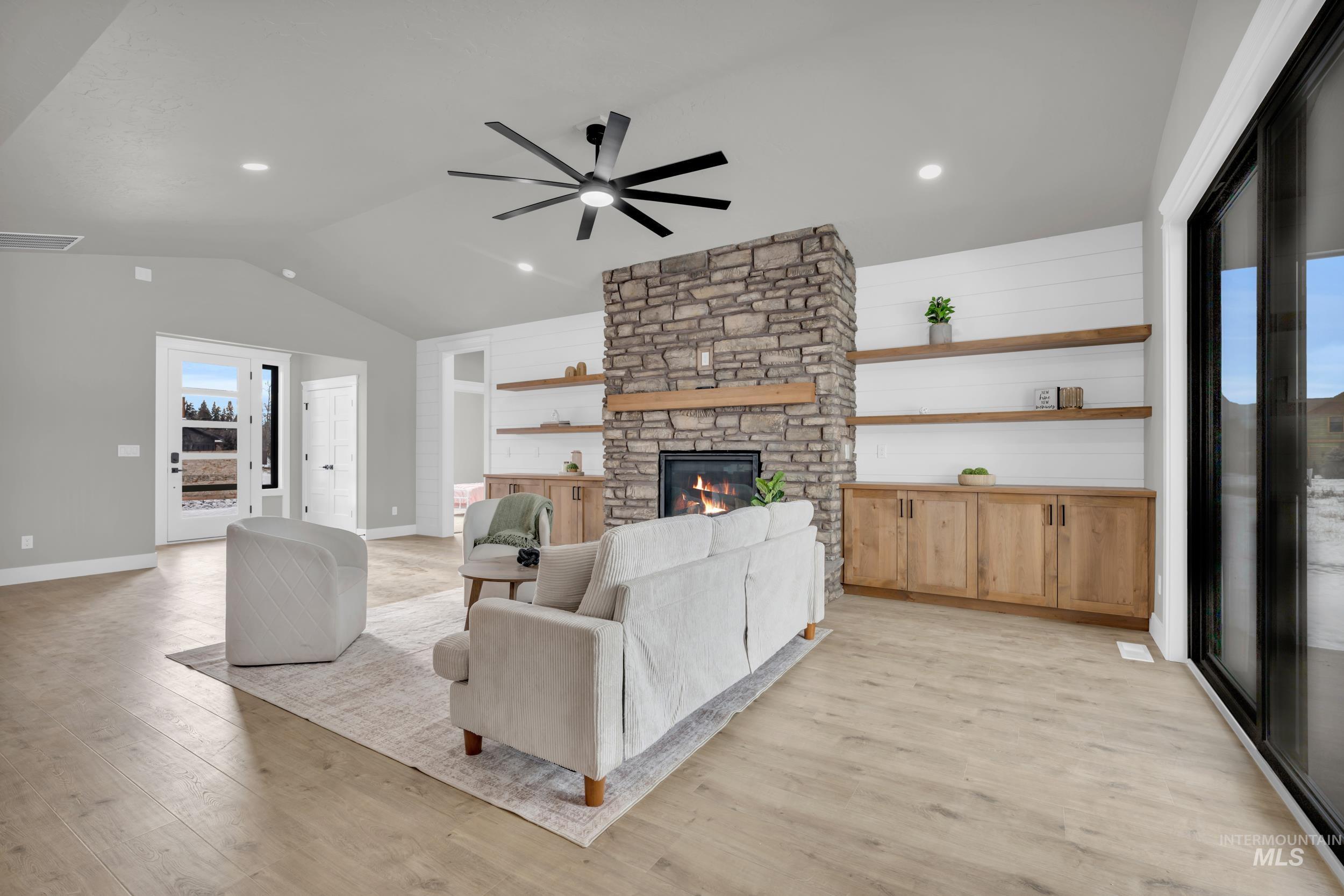 Living room with vaulted ceiling, recessed lighting, ceiling fan, light wood-type flooring, and a fireplace