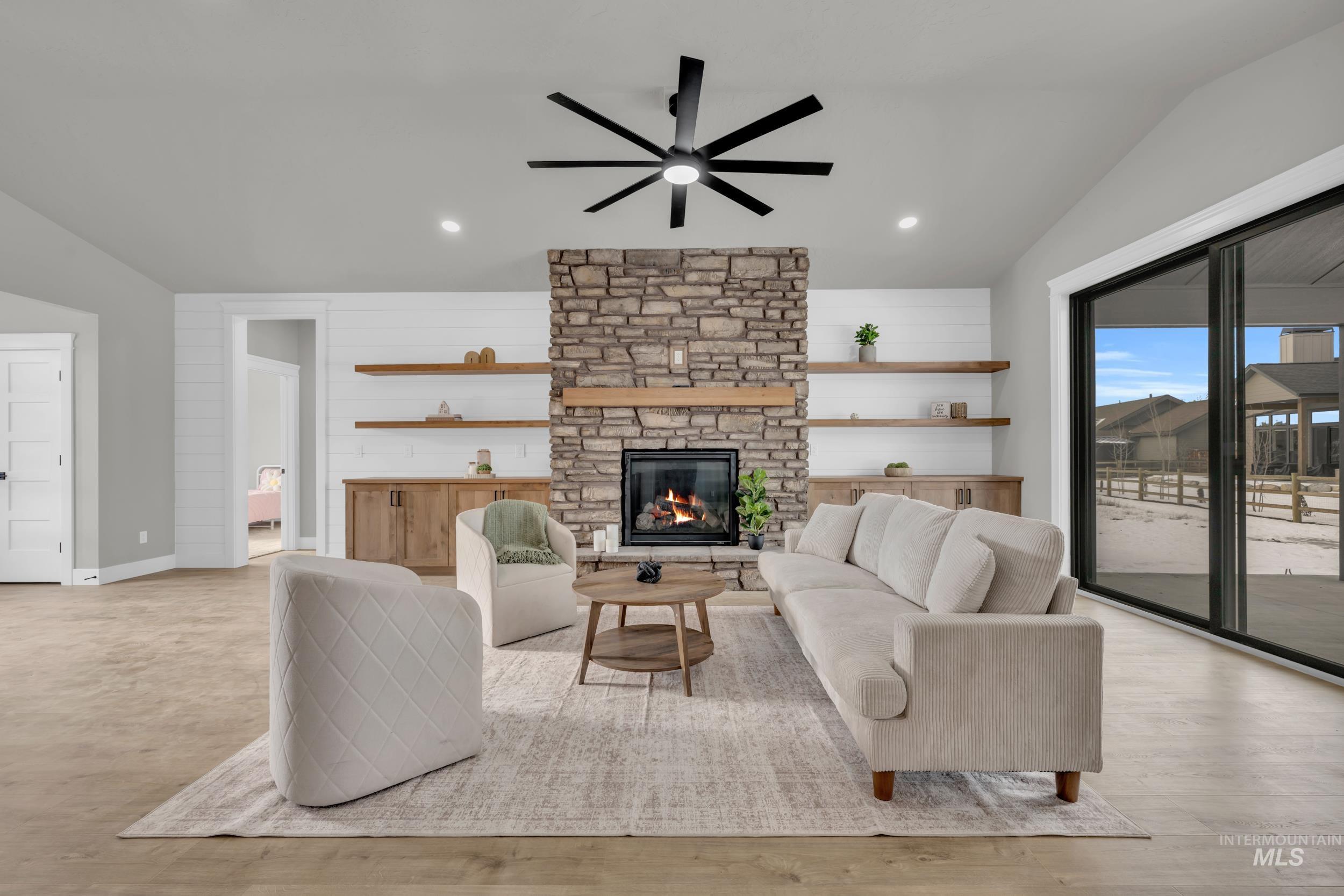 Living room with vaulted ceiling, a fireplace, recessed lighting, a ceiling fan, and light wood-style flooring