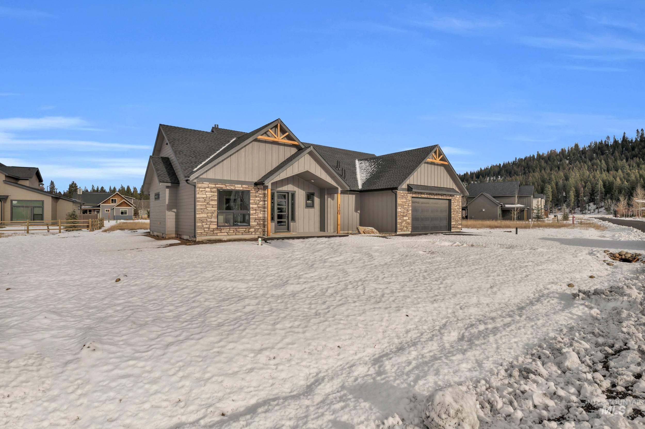 View of front of home featuring board and batten siding, an attached garage, stone siding, and covered porch
