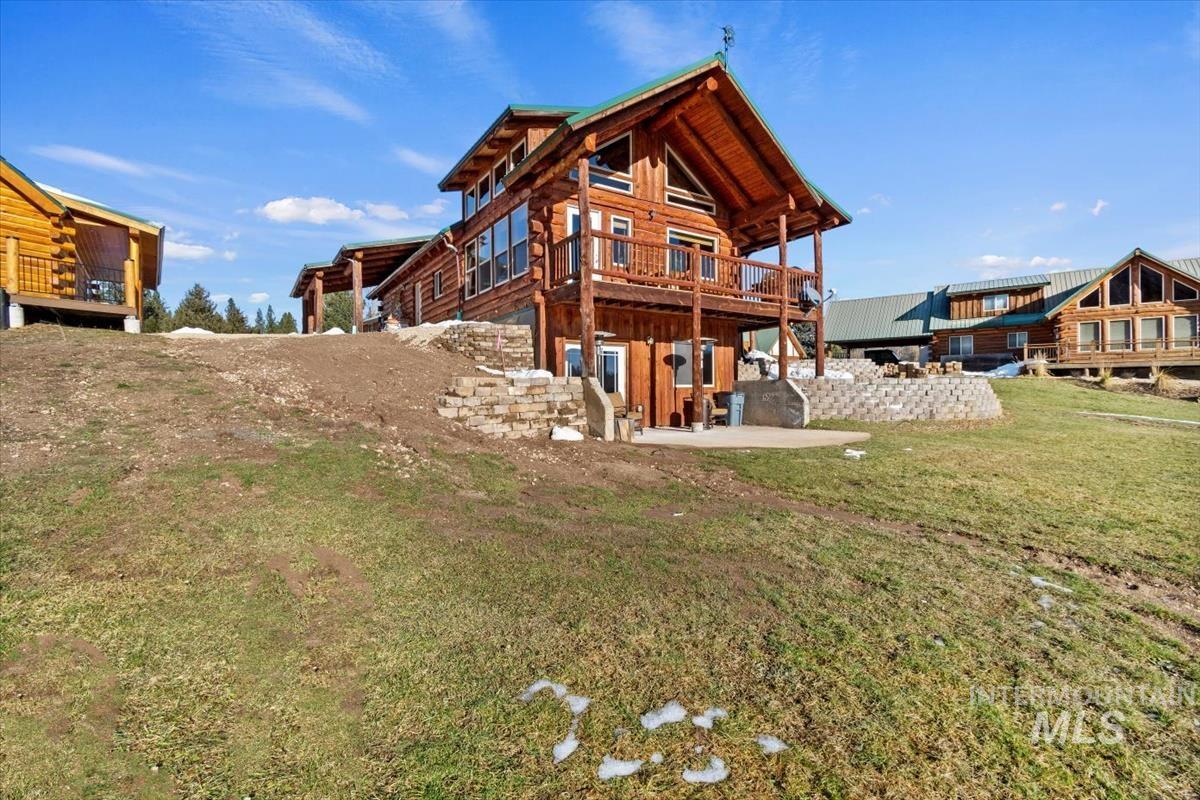 Rear view of house with a patio area, a deck, log siding, and a yard