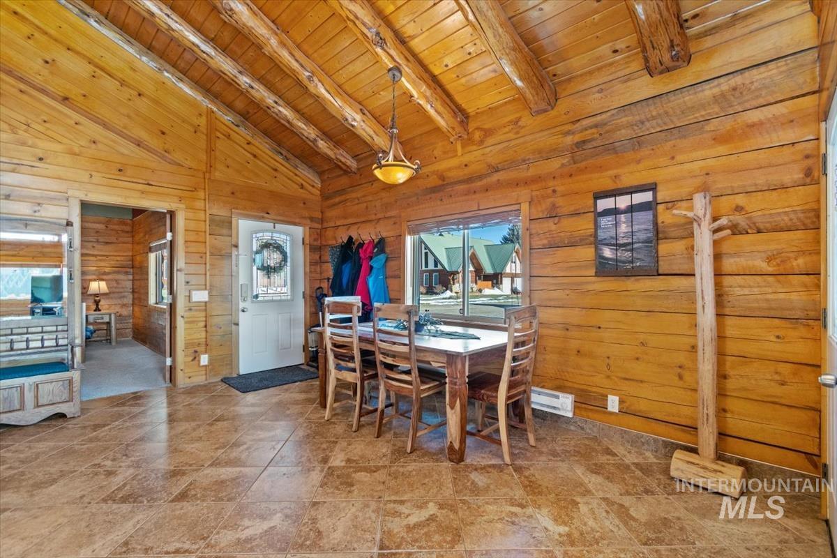 Dining space featuring a wood ceiling with exposed beams, wooden walls, and high vaulted ceiling