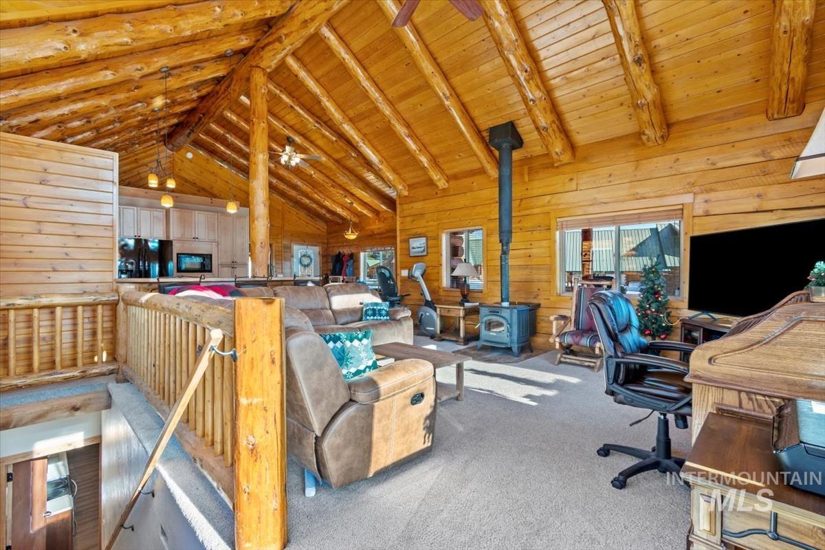 Office featuring wood walls, a wood stove, wooden ceiling, and a ceiling fan