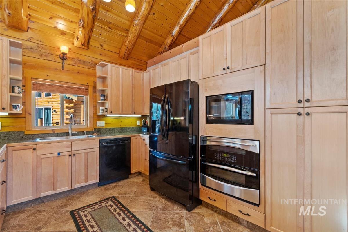 Kitchen with light brown cabinets, open shelves, wooden ceiling, black appliances, and dark countertops