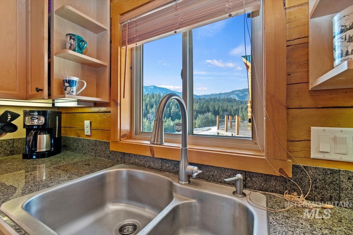 Kitchen view of open shelves and dark stone counters
