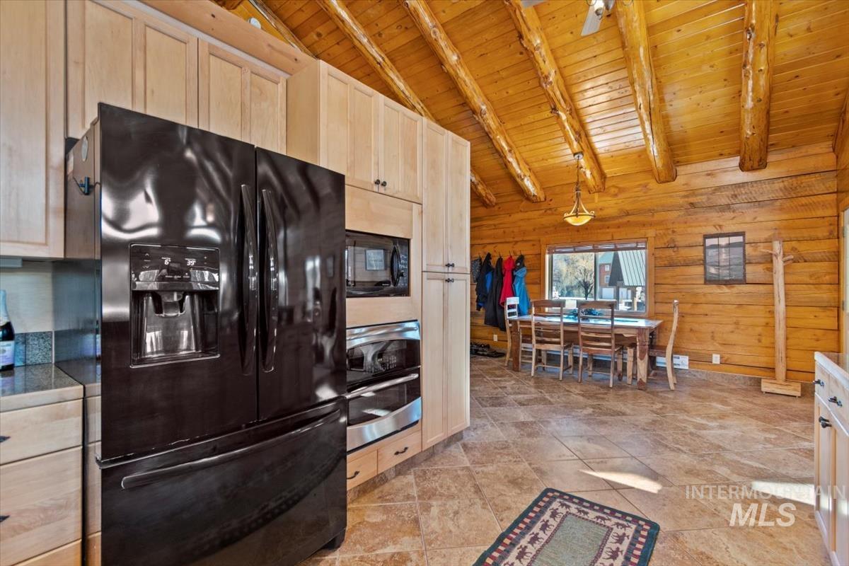 Kitchen featuring light brown cabinets, black appliances, wooden ceiling, wooden walls, and dark countertops