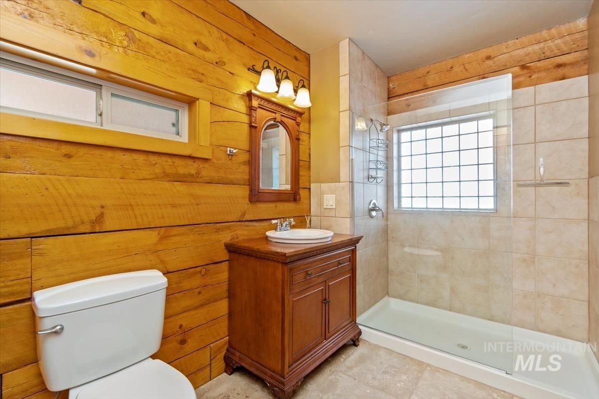 Bathroom with wooden walls, a tile shower, and vanity
