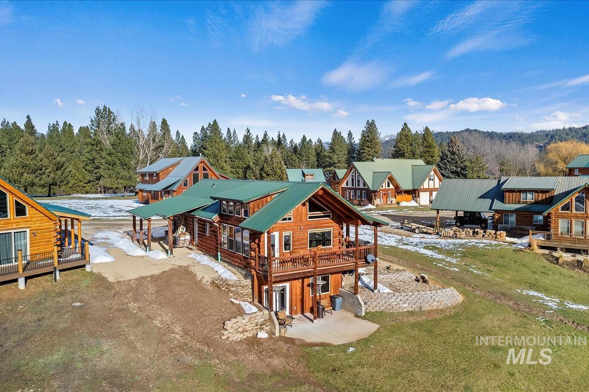 Back of property featuring a patio area, a wooden deck, log siding, and a lawn
