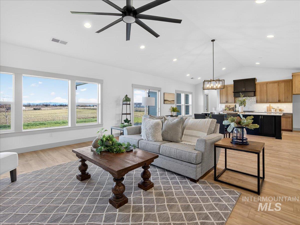 Living area featuring light wood-type flooring, a chandelier, lofted ceiling, and a ceiling fan