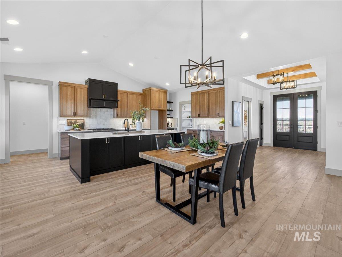 Dining space with french doors, vaulted ceiling, light wood-style flooring, a chandelier, and recessed lighting
