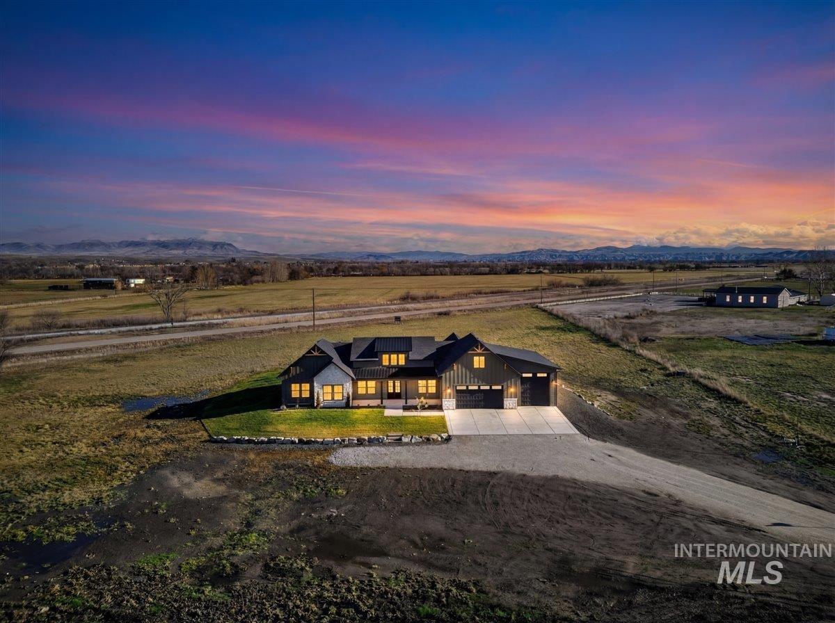 View of front of home featuring driveway, board and batten siding, a front yard, a mountain view, and a garage