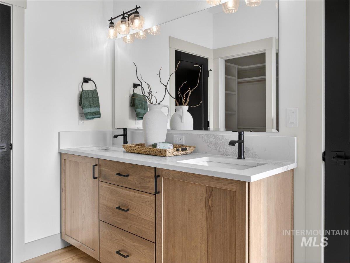Full bathroom featuring double vanity, a walk in closet, and light wood-style flooring