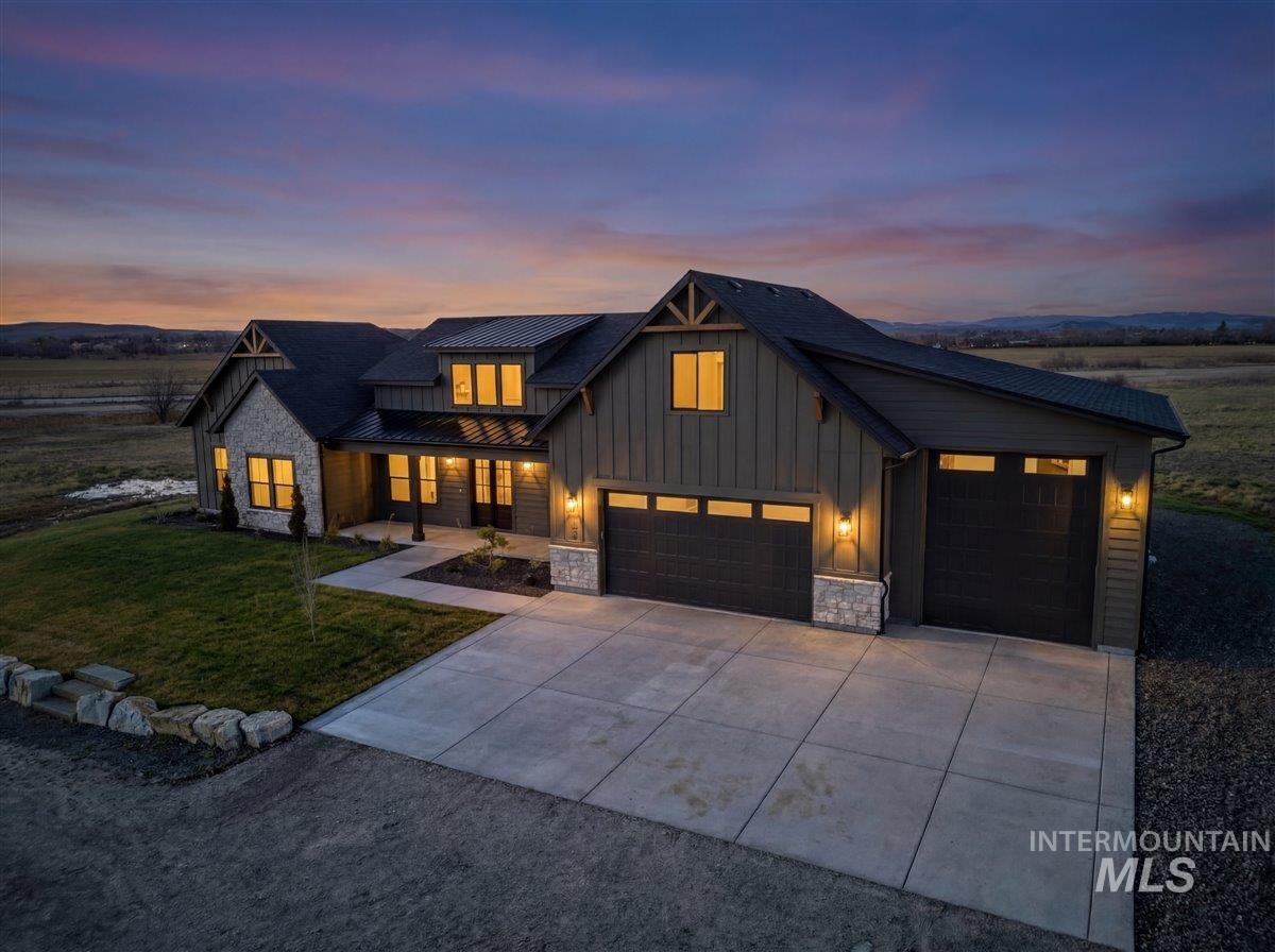 Modern inspired farmhouse featuring stone siding, covered porch, a lawn, board and batten siding, and concrete driveway