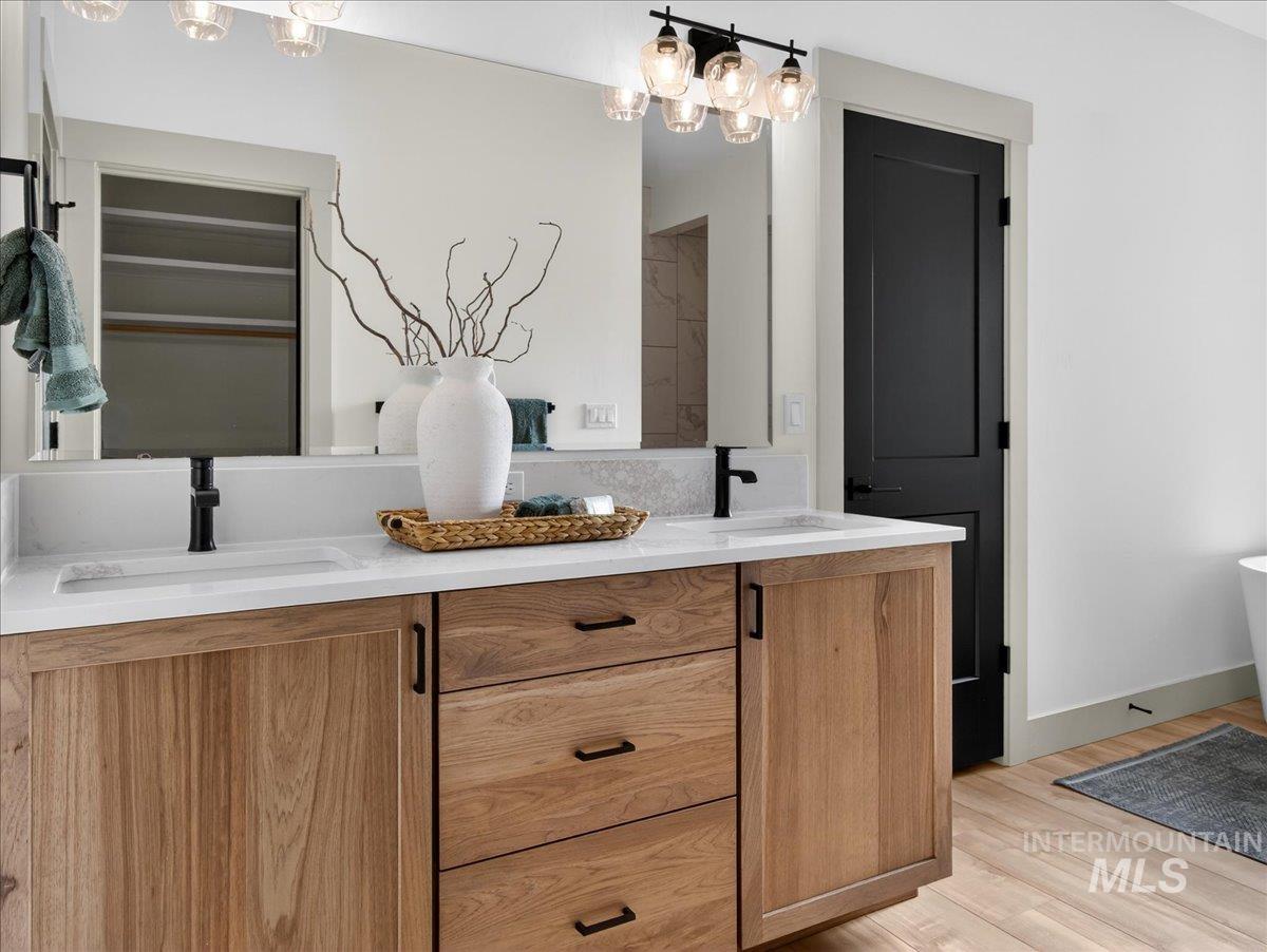 Full bathroom featuring double vanity, light wood-style flooring, and a chandelier