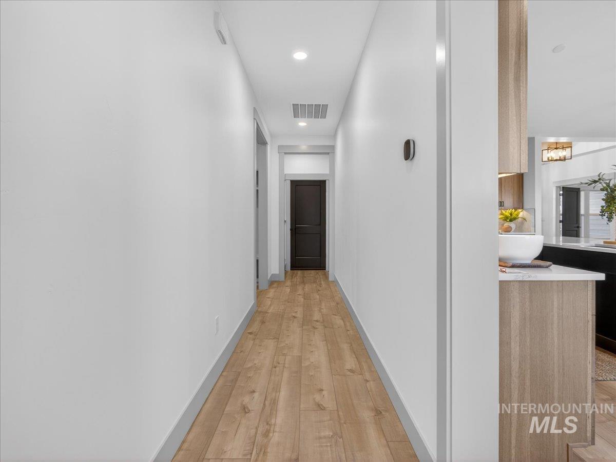 Hallway with light wood finished floors, recessed lighting, and a chandelier