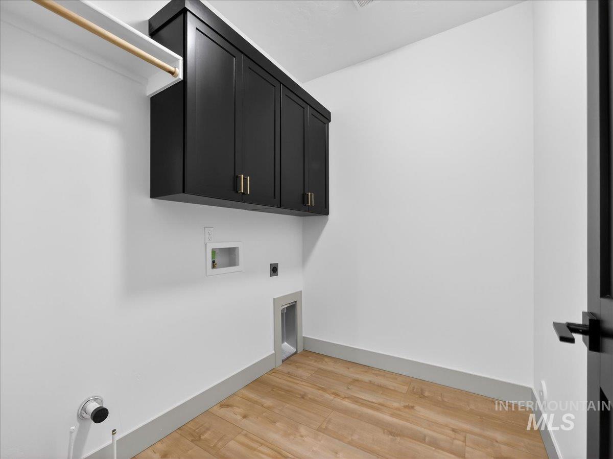 Washroom with cabinet space, washer hookup, light wood-style floors, and electric dryer hookup