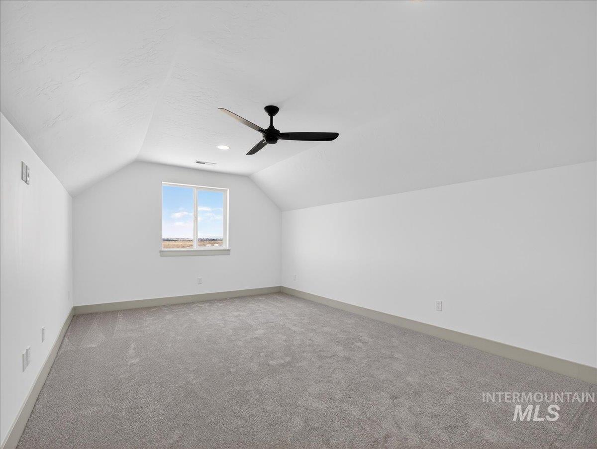 Bonus room with vaulted ceiling, light carpet, a ceiling fan, and a textured ceiling