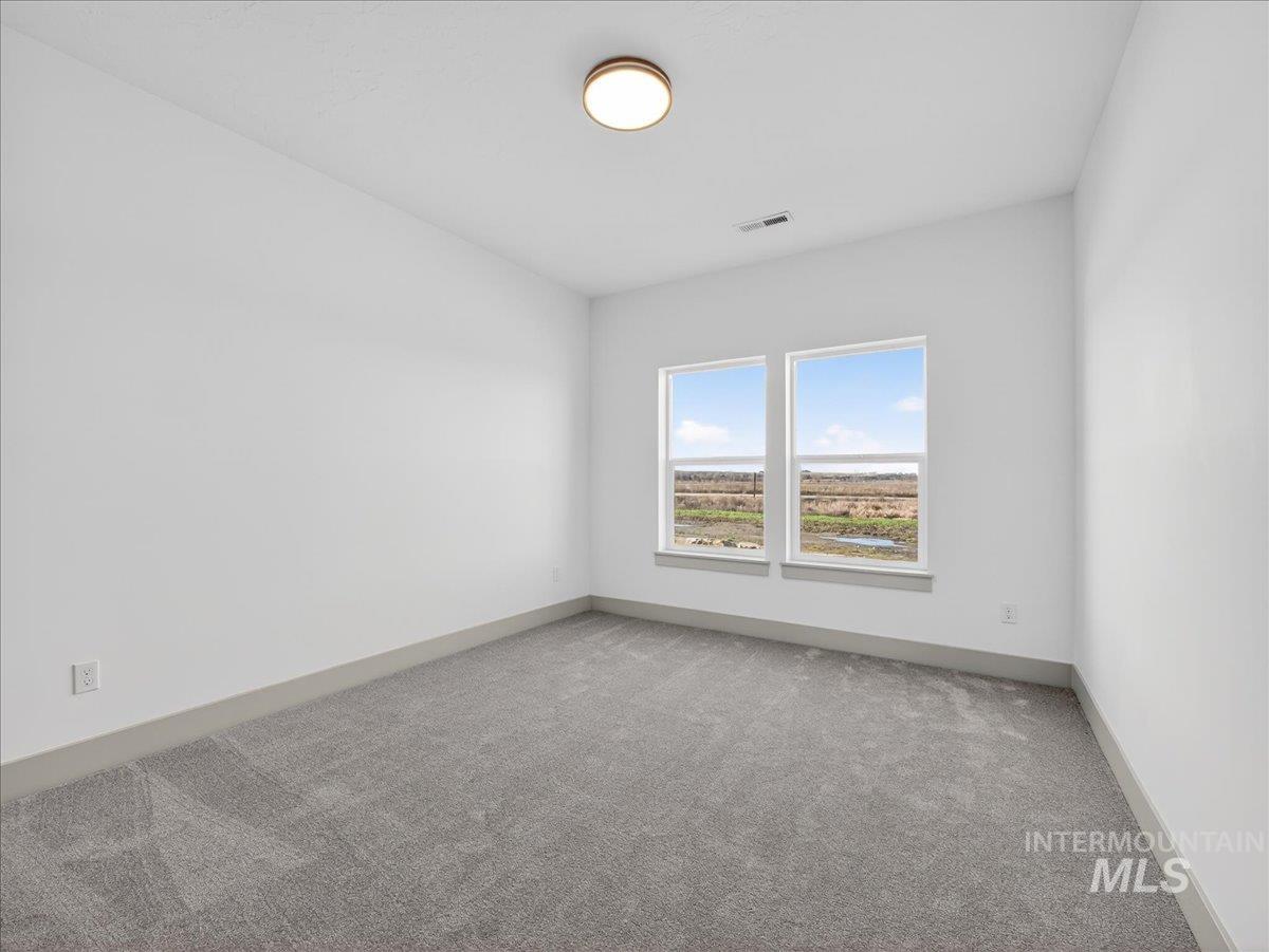 Empty room featuring light carpet and baseboards