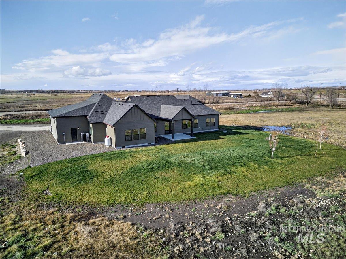 View of front of house with a patio area, a front lawn, a shingled roof, and board and batten siding
