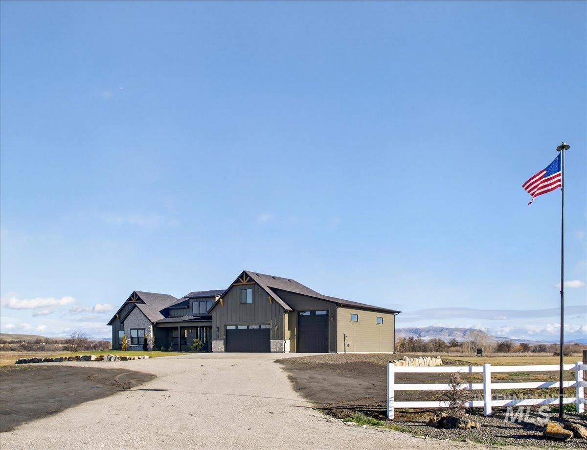 View of front facade featuring stone siding, board and batten siding, and dirt driveway