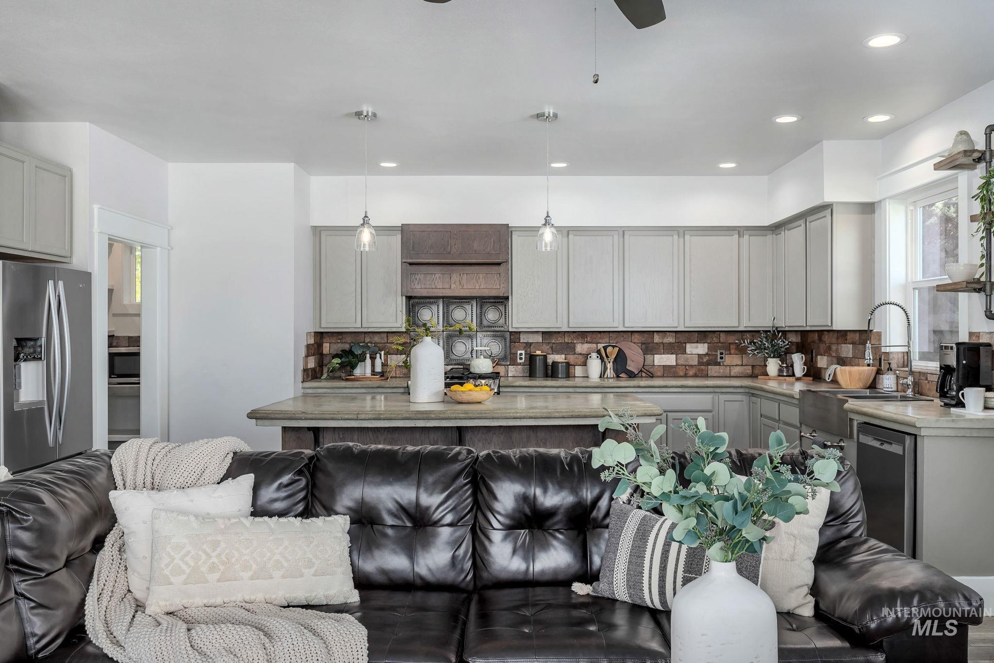 Kitchen with gray cabinets, hanging light fixtures, stainless steel appliances, tasteful backsplash, and recessed lighting