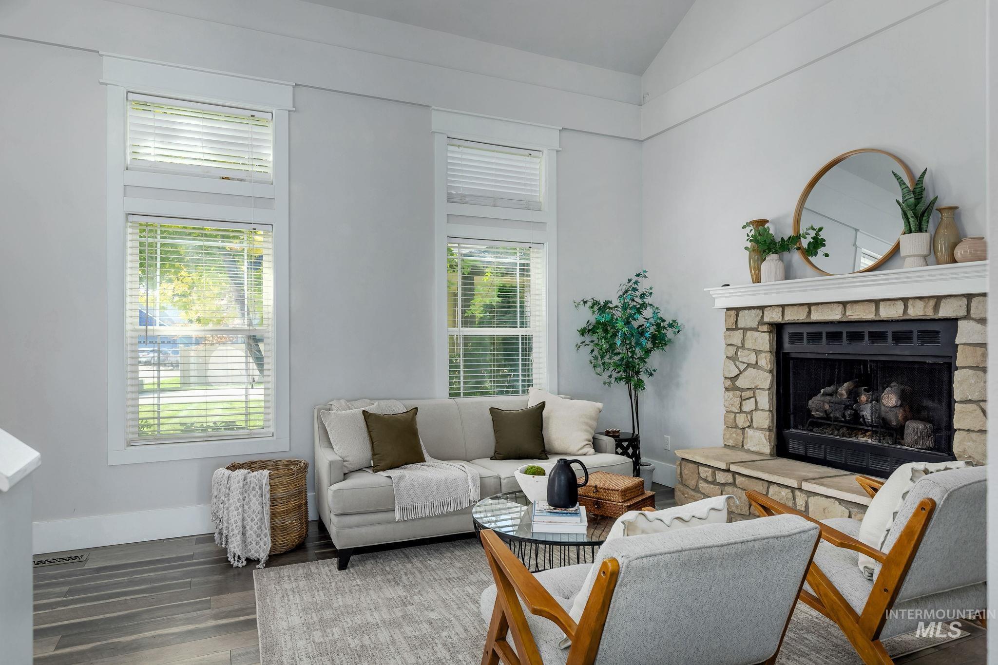 Living area with a stone fireplace, wood finished floors, and high vaulted ceiling