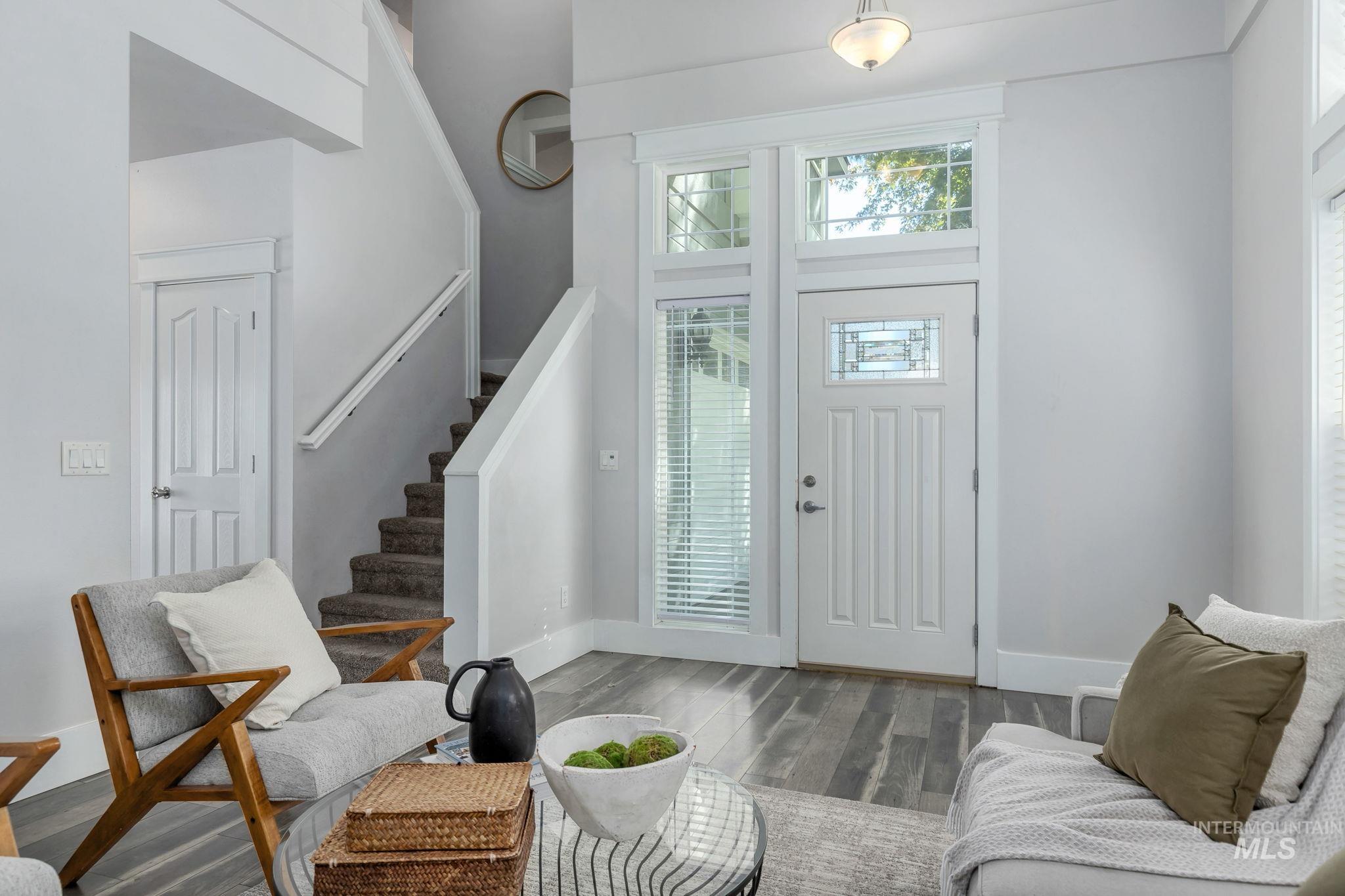 Foyer entrance with stairway, wood finished floors, and a high ceiling