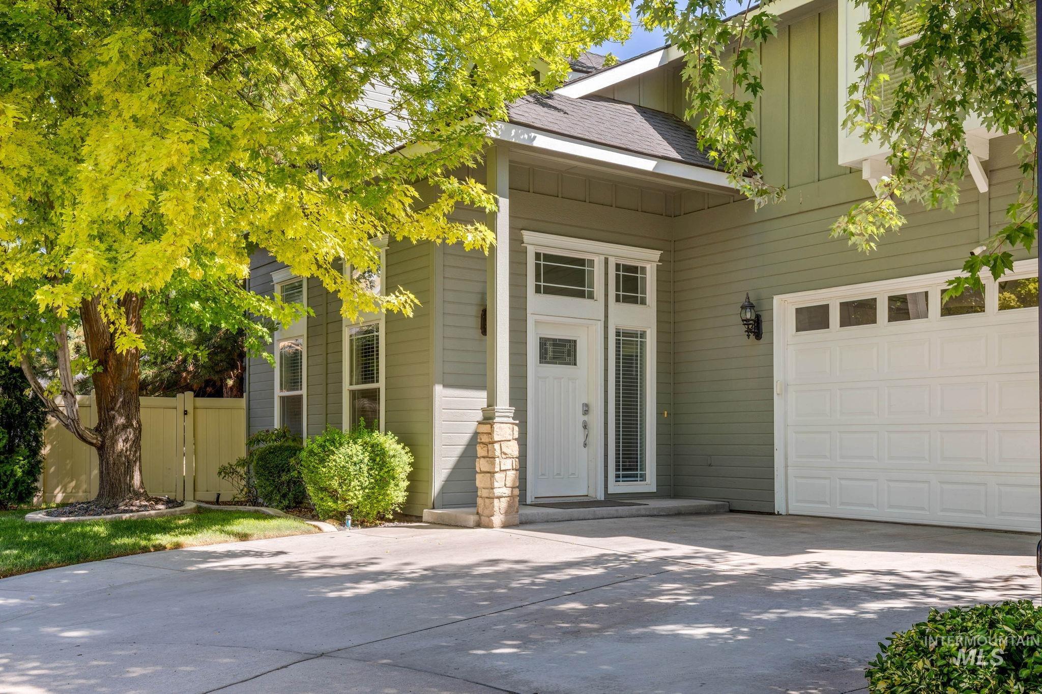Property entrance featuring a garage, a shingled roof, and concrete driveway