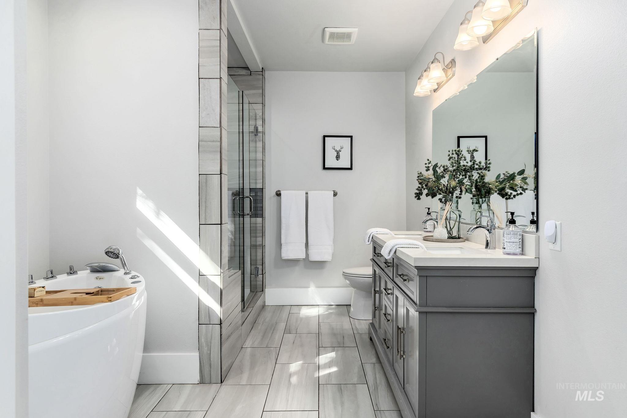 Bathroom featuring a freestanding bath, double vanity, and a shower stall