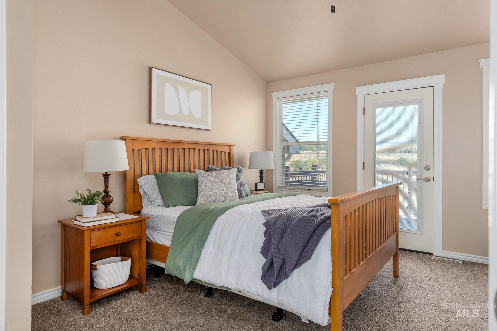 Carpeted bedroom featuring vaulted ceiling and access to exterior