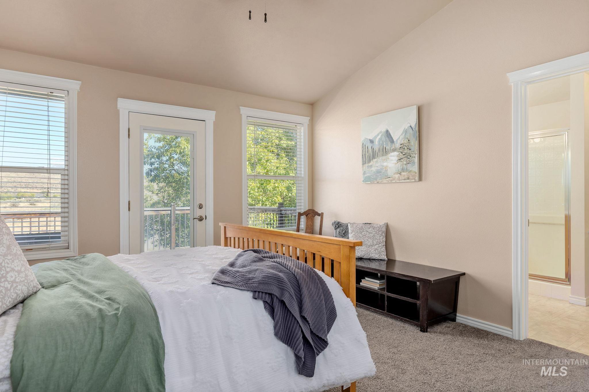Carpeted bedroom with vaulted ceiling, access to exterior, and ensuite bathroom