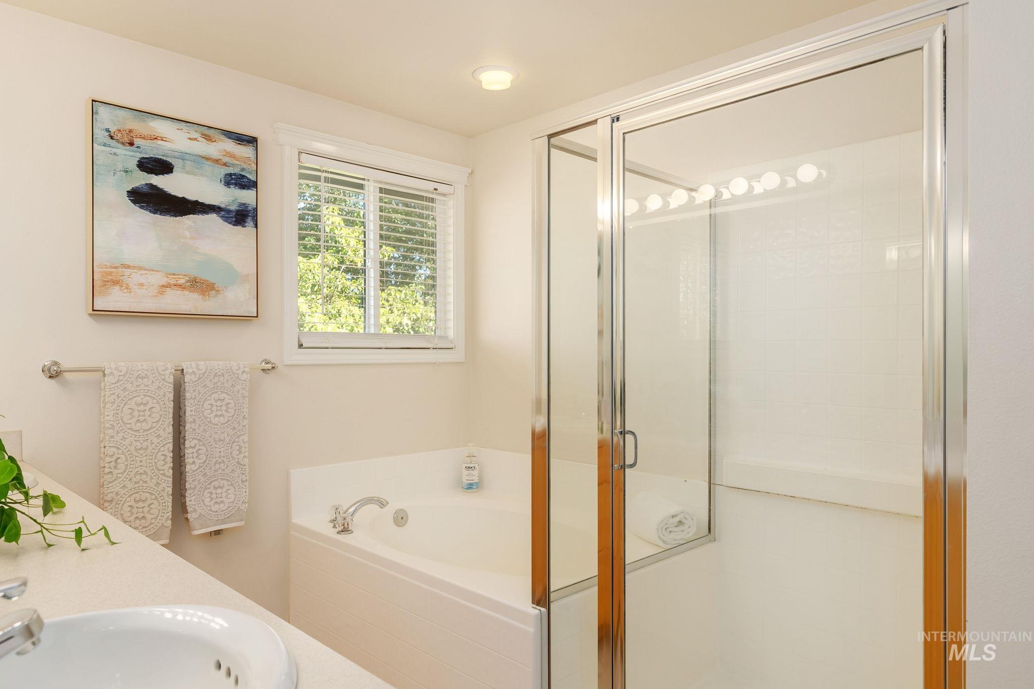 Bathroom featuring a bath, a stall shower, and vanity