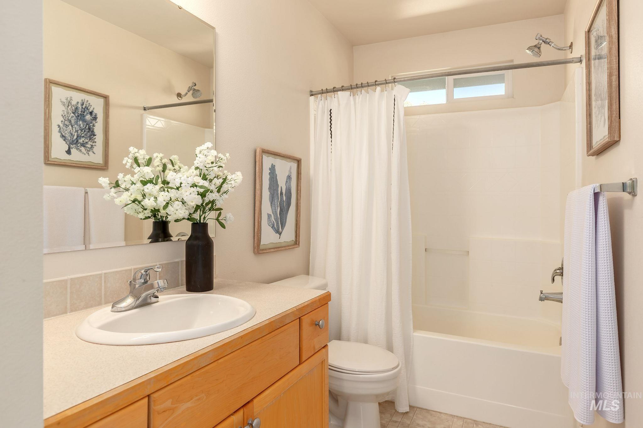 Bathroom featuring shower / tub combo, vanity, and light tile patterned floors