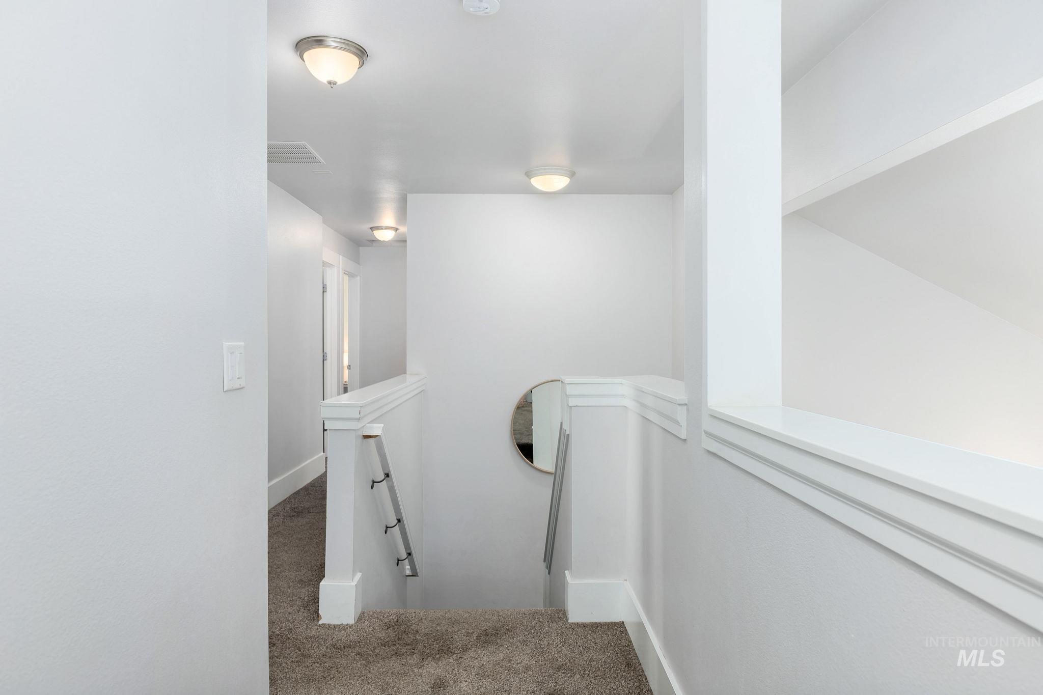 Corridor with an upstairs landing and carpet flooring