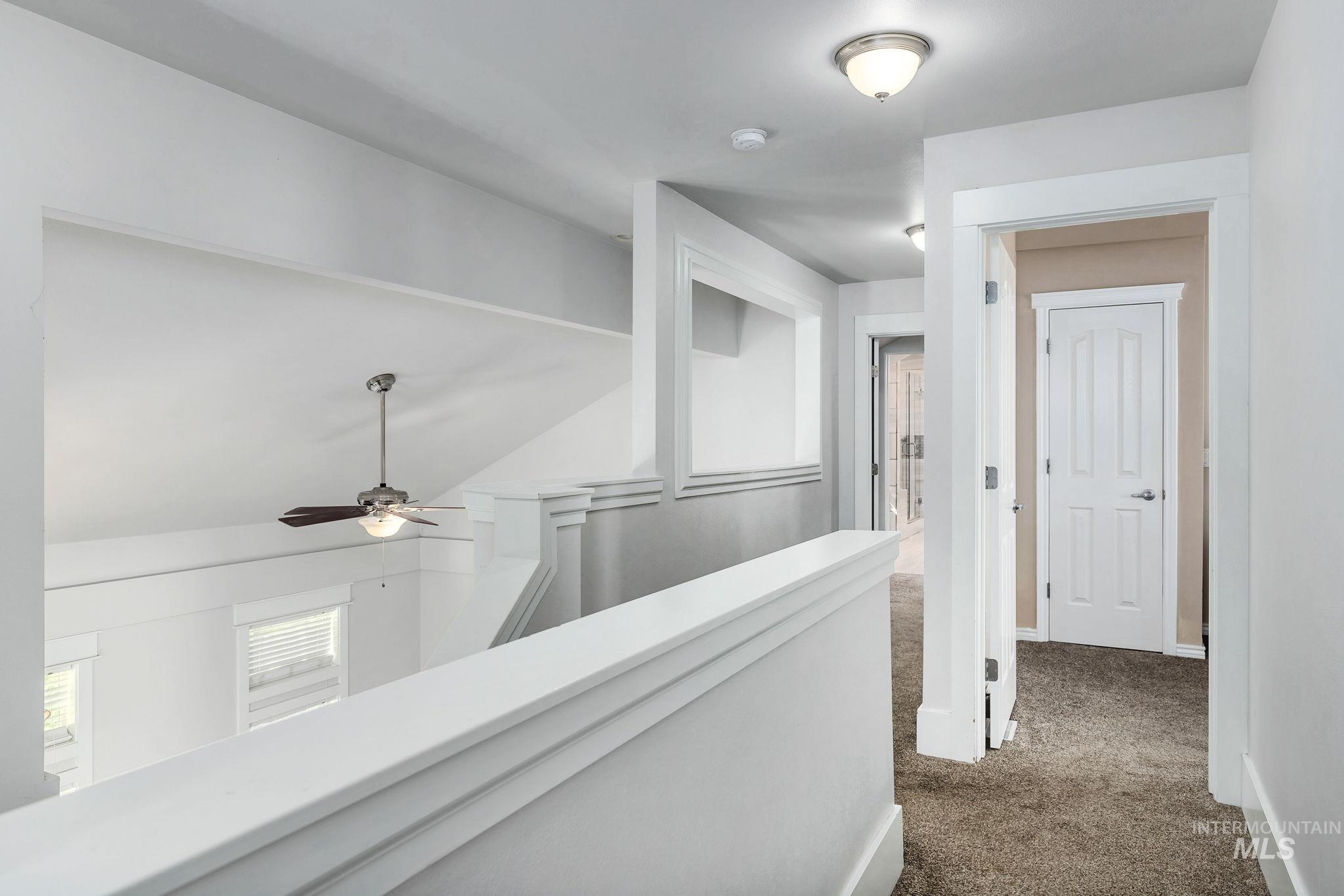 Hallway with dark carpet and an upstairs landing
