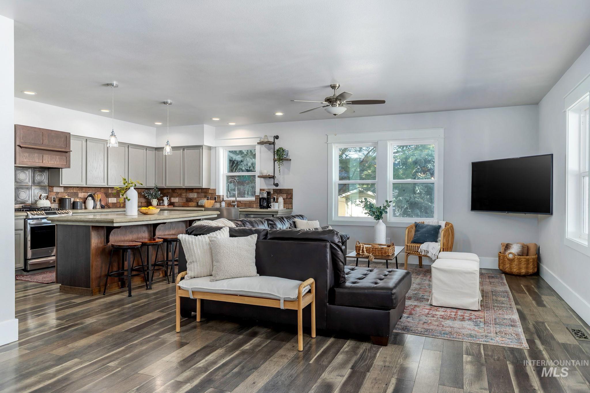 Living area featuring plenty of natural light, dark wood-style flooring, a ceiling fan, and recessed lighting