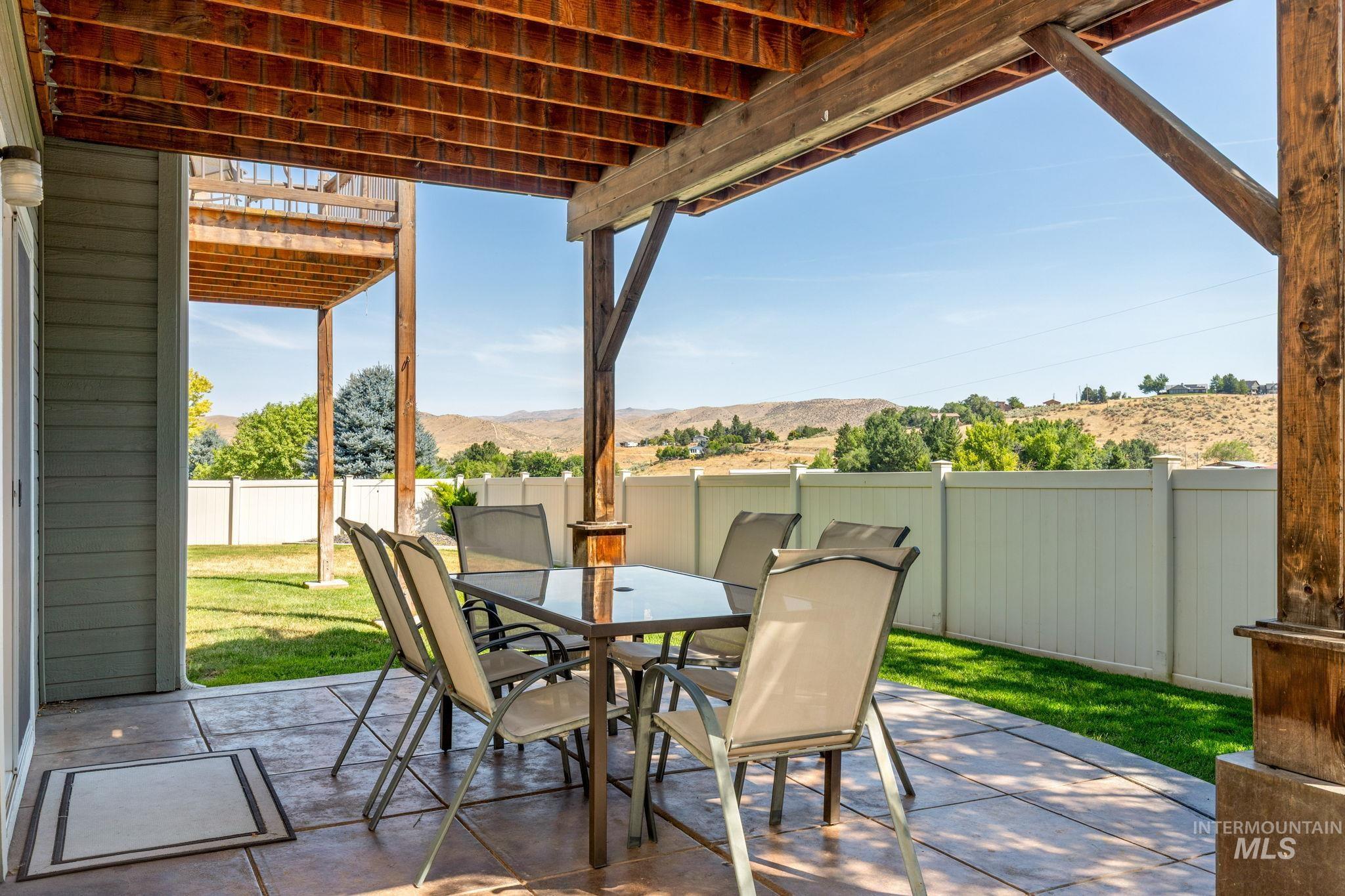 Fenced backyard featuring a patio, outdoor dining area, and a mountain view