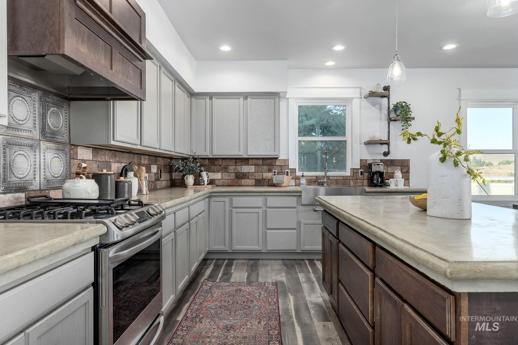 Kitchen with stainless steel range with gas stovetop, dark brown cabinets, decorative backsplash, dark wood-type flooring, and decorative light fixtures