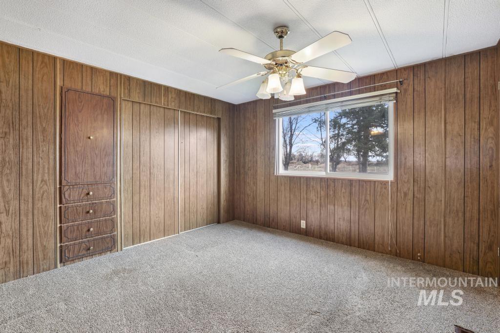 Spare room featuring carpet flooring, wooden walls, and a ceiling fan
