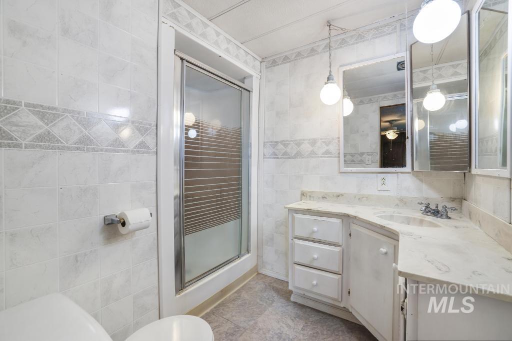 Full bathroom with vanity, a shower stall, and tile walls