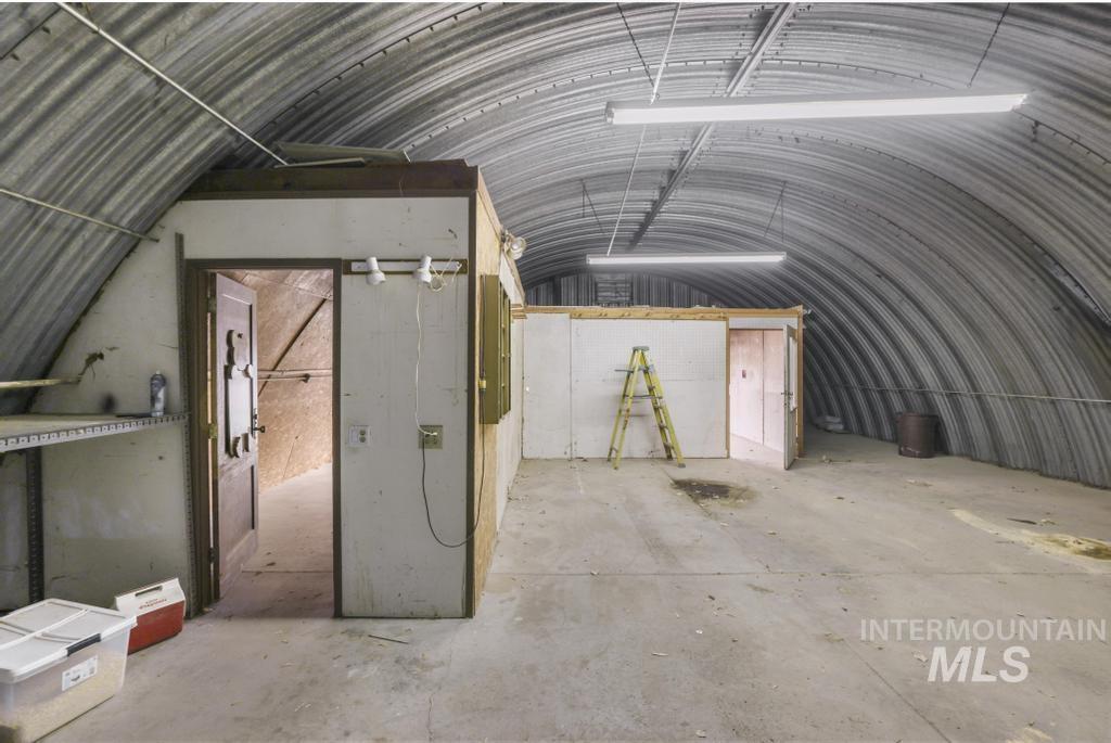 Misc room featuring vaulted ceiling, unfinished concrete floors, metal wall, and a garage